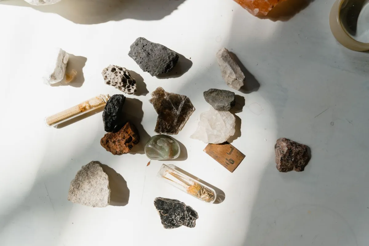 Assorted rough rocks and mineral samples laid out on a sunlit table