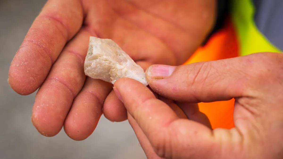 Hand turning over a rough quartz specimen to check it for cracks